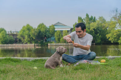 Young man with dog sitting on grass