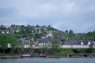Houses by river amidst buildings against sky