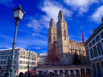 Low angle view of buildings against blue sky on sunny day in city