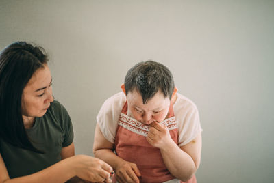 Lifestyle, education. elderly woman with down syndrome tries her cooked food in class with a teacher