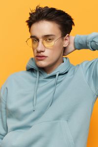 Portrait of young man standing against yellow background