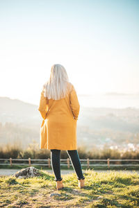 Rear view of woman standing on field against sky