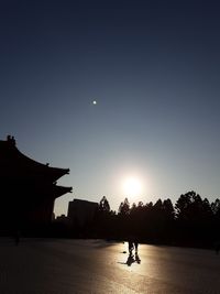 Silhouette people at town against sky during sunset