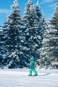 Full length of boy skiing against snow covered pine trees