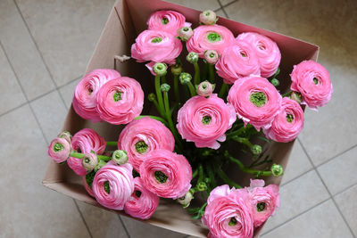 Pink ranunculus bouquet in a cardboard box on the floor. top view. for flower delivery