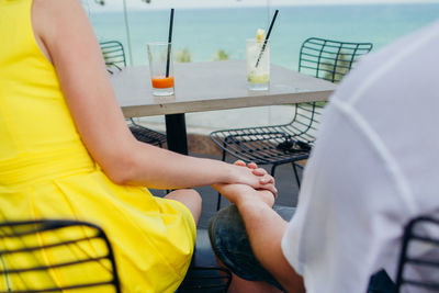 Midsection of people holding drinks on table