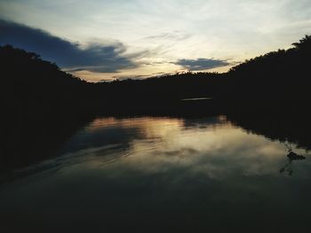 Silhouette trees by lake against sky during sunset