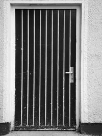 Frontal view of a door in a rough plastered wall in black and white.