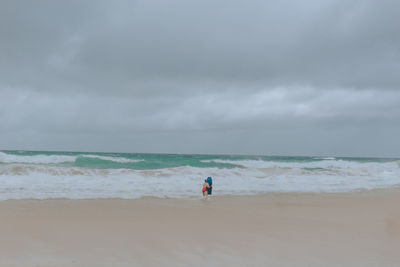 Rear view of man on beach against sky