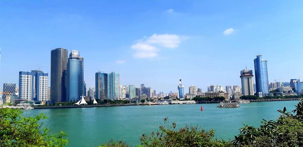 City by river and buildings against sky