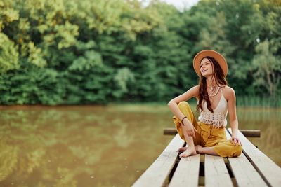 Portrait of young woman standing against lake