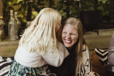 Daughter whispering something in mother's ear