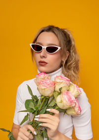 Portrait of woman wearing sunglasses against red background