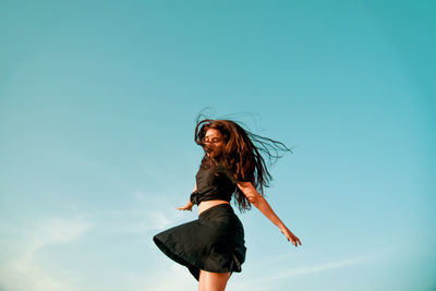 Low angle view of woman standing against sky