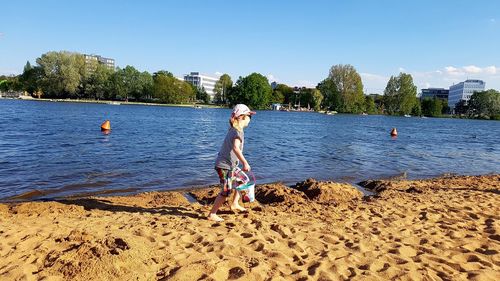 Side view of girl walking with bucket at sandy beach