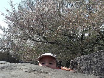 Portrait of boy with arms raised against trees