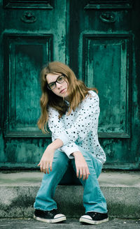 Full length of woman sitting against door