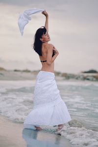Woman with top wading in sea against sky