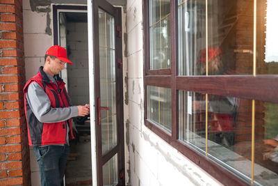 Side view of young woman standing by window