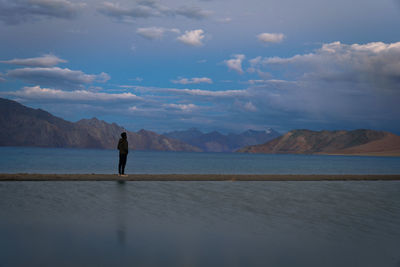Full length of man standing by lake against sky