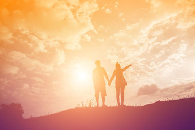 Silhouette friends standing against sky during sunset