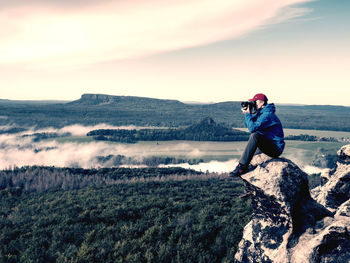 Side view of man looking at mountain against sky