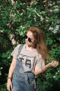 Cheerful woman standing against plants