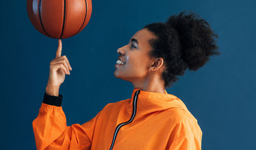 Side view of man holding basketball hoop against sky