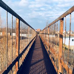 Empty footbridge against sky