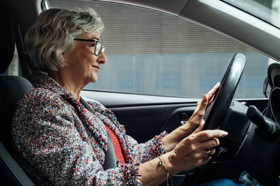 Smiling senior businesswoman driving car