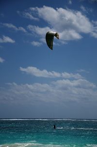 Person paragliding in sea against sky