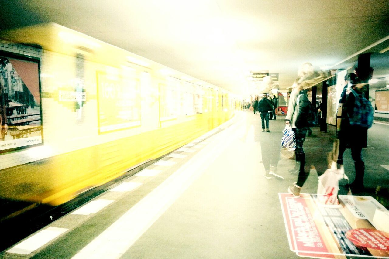 transportation, mode of transport, public transportation, railroad station platform, travel, men, railroad station, rail transportation, land vehicle, motion, on the move, blurred motion, train - vehicle, lifestyles, city life, indoors, illuminated, text, railroad track