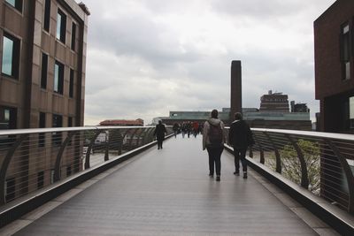 Men on bridge in city against sky