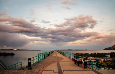 Pier on sea against cloudy sky