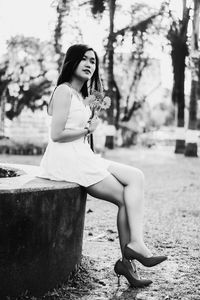 Young woman holding flowers while sitting in park