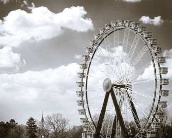 Low angle view of ferris wheel against cloudy sky