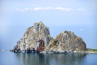 Rocky cliff on sea against sky