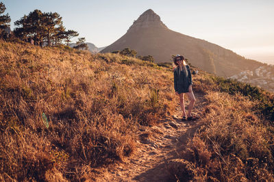 Woman sitting on mountain against sky during sunset