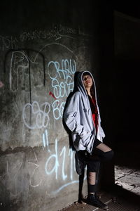 Man standing by graffiti on wall at night