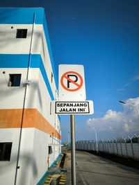 Low angle view of road sign against blue sky