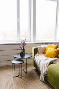 Black coffee table with vases and branches with leaves standing on the carpet in a real photo