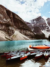 Boats moored on lake against rocky mountains