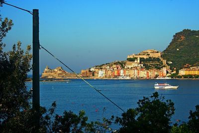 Cityscape by sea against clear blue sky