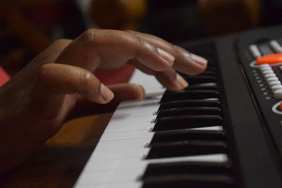 Cropped hand playing piano in darkroom