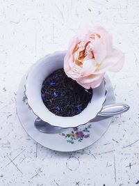 Close-up of black tea leaves in cup and rose on table