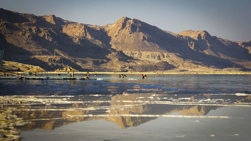 People enjoying in sea against mountain range