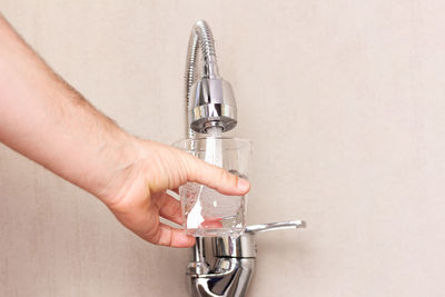 Cropped hand of person repairing equipment against white background