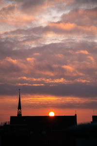 Silhouette building against dramatic sky during sunset