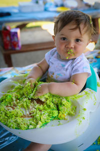 Portrait of cute baby boy eating cake on table