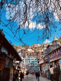 People on street amidst buildings in city against sky